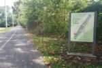Paved trail next to row of trees with sign for River Bluff Trail